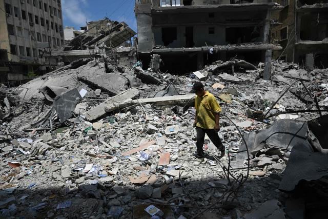 A man walks on the debris of a flattened building as workers begin to remove the rubble from the site of an earlier Israeli military strike on a neighbourhood in the southern Lebanese coastal city of Tyre on June 23, 2026. On June 22, 2026, mediators Pakistan and Qatar said that Tehran and Washington had agreed to set up a "de-confliction cell" to limit flare-ups in Lebanon following talks in Switzerland on ending the wider Middle East war, which Tehran has linked to halting the parallel conflict in Lebanon. (Photo by Joseph EID / AFP) / 