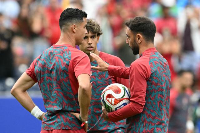 Portugal's forward #07 Cristiano Ronaldo (L)< Portugal's forward #11 Joao Felix (C) and Portugal's midfielder #08 Bruno Fernandes (R) speak during warm up prior to the  2026 World Cup Group K football match between Portugal and Uzbekistan at the Houston Stadium in Houston on June 23, 2026.  (Photo by RONALDO SCHEMIDT / AFP)