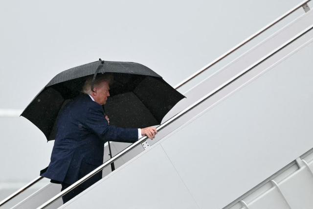 US President Donald Trump holds an umbrella as he boards Air Force One under the rain at Joint Base Andrews, Maryland on June 23, 2026. Trump is traveling to Macungie, Pennsylvania to speak at a Mack Trucks facility. (Photo by Mandel NGAN / AFP)