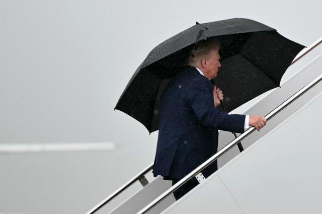 US President Donald Trump holds an umbrella as he boards Air Force One under the rain at Joint Base Andrews, Maryland on June 23, 2026. Trump is traveling to Macungie, Pennsylvania to speak at a Mack Trucks facility. (Photo by Mandel NGAN / AFP)