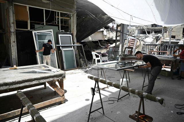 Aluminium workers repair doors an windows belonging to homes and businesses damaged during the earlier Israeli military strikes on the southern Lebanese coastal city of Tyre on June 23, 2026. On June 22, 2026, mediators Pakistan and Qatar said that Tehran and Washington had agreed to set up a "de-confliction cell" to limit flare-ups in Lebanon following talks in Switzerland on ending the wider Middle East war, which Tehran has linked to halting the parallel conflict in Lebanon. (Photo by Joseph EID / AFP) / 