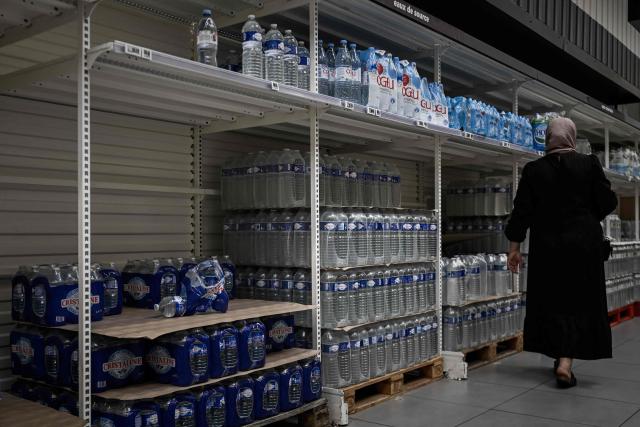 A woman walks past shelves of bottled water at a supermarket during a heatwave in Bordeaux, south-western France on June 23, 2026. France on June 23, 2026 experienced its hottest day since measurements began in 1947, the national weather agency said. A deadly heatwave has battered France since last week, disrupting daily life and forcing the early closure of top Paris tourist hotspots. (Photo by Philippe LOPEZ / AFP)