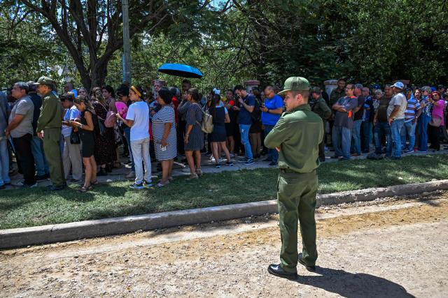 People line up in front of the Ministry of the Revolutionary Armed Forces to pay tribute to Commander Ramiro Valdés during his funeral in Havana on June 23, 2026. Ramiro Valdes Menendez, a close associate of brothers Fidel and Raul Castro and founder of the Cuban intelligence services, has died at the age of 94, Cuban President Miguel Diaz-Canel announced on June 21, 2026. (Photo by YAMIL LAGE / AFP)