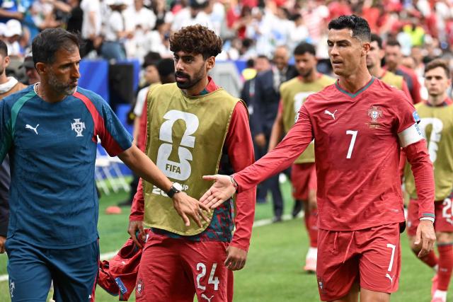 Portugal's forward #07 Cristiano Ronaldo (R) is congratulated by a Portugal team staff member as he leaves the pitch at half-time of the 2026 World Cup Group K football match between Portugal and Uzbekistan at the Houston Stadium in Houston on June 23, 2026.  (Photo by Paul ELLIS / AFP)