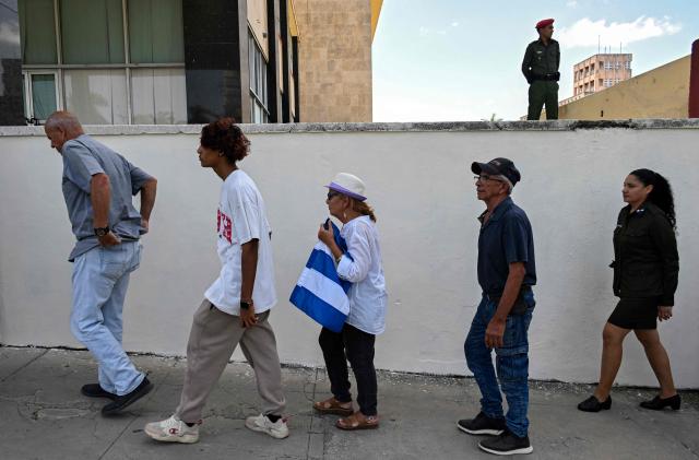 People line up in front of the Ministry of the Revolutionary Armed Forces to pay tribute to Commander Ramiro Valdés during his funeral in Havana on June 23, 2026. Ramiro Valdes Menendez, a close associate of brothers Fidel and Raul Castro and founder of the Cuban intelligence services, has died at the age of 94, Cuban President Miguel Diaz-Canel announced on June 21, 2026. (Photo by YAMIL LAGE / AFP)