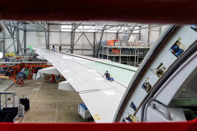 (FILES) An employee of Elbe Flugzeugwerke GmbH works on a wing of a Lufthansa Airbus A380 in Dresden, eastern Germany on May 27, 2026. The European Union Aviation Safety Agency (EASA) has ordered inspections of 16 Airbus A380 aircraft, including five on an urgent basis, after cracks were discovered in the wing structure of one plane, the aircraft manufacturer Airbus confirmed on June 23, 2026. (Photo by Jens SCHLÜTER / AFP)