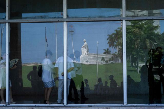 View of the Cuban flag at half-mast reflected on the window of the Ministry of the Revolutionary Armed Forces, where the wake of Commander Ramiro Valdes is being held, in Havana, on June 23, 2026. Ramiro Valdes Menendez, a close associate of brothers Fidel and Raul Castro and founder of the Cuban intelligence services, has died at the age of 94, Cuban President Miguel Diaz-Canel announced on June 21, 2026. (Photo by Pablo PORCIUNCULA / AFP)