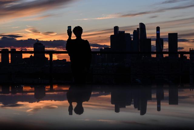 A man takes a selfie on an observation deck at sunset, with the Moscow skyline in the background, on June 23, 2026. (Photo by Igor IVANKO / AFP)