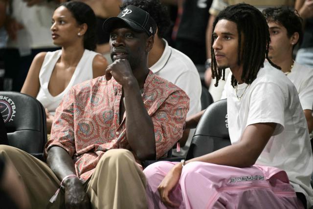 French actor Omar Sy (L) attends the French Ligue Nationale de Basket (LNB Elite) Pro A match 5 of the final between Paris Basketball and AS Monaco Basket, at the Adidas Arena in Paris on June 23, 2026. James is wearing the number 32, which is usually worn by his teammate Matthew Strazel, who is absent for this decisive match after being handed a one-match ban (plus a suspended one) on June 22, 2026 by the National Basketball League (LNB) disciplinary committee. (Photo by JULIEN DE ROSA / AFP)