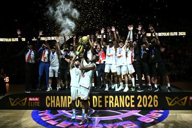 AS Monaco's players and coaching staff celebrate becoming the French Ligue Nationale de Basket (LNB Elite) Champions as they lift the trophy after their match 5 final game against Paris Basketball at the Adidas Arena in Paris on June 23, 2026. (Photo by JULIEN DE ROSA / AFP)
