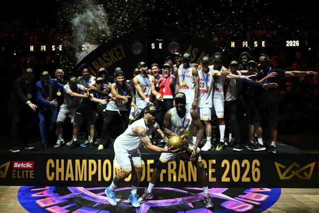 AS Monaco's players and coaching staff celebrate becoming the French Ligue Nationale de Basket (LNB Elite) Champions as they lift the trophy after their match 5 final game against Paris Basketball at the Adidas Arena in Paris on June 23, 2026. (Photo by JULIEN DE ROSA / AFP)