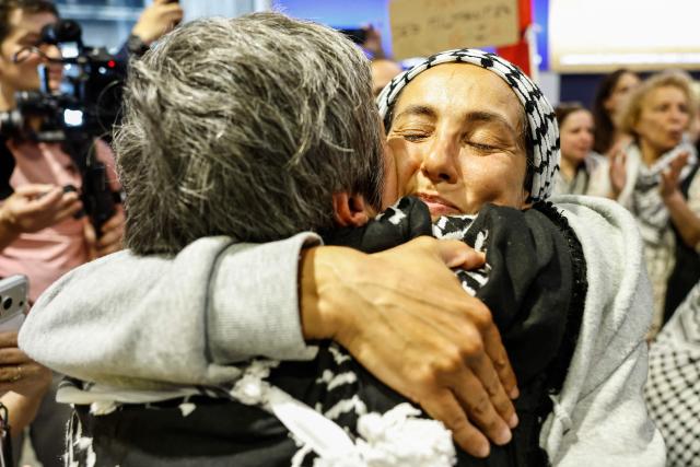 (FILES) French activist Meriem Hadjal detained and deported by Israel following the interception of their Gaza-bound flotilla hugs a relative as they arrive at Roissy Charles de Gaulle airport near Paris on May 22, 2026. International condemnation has mounted since May 2026 regarding the treatment of these 430 activists, including around 30 French nationals. France and Italy have launched judicial investigations into allegations of torture and war crimes, which will seek to establish who is responsible, whilst Australia has announced an independent inquiry. The Israeli authorities have rejected these accusations. (Photo by SIMON WOHLFAHRT / AFP)