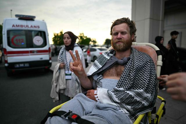 (FILES) A member of the Global Sumud Flotilla headed for Gaza and arrested and deported by Israel gestures the V-sign as he is brought out of a terminal on a wheelchair following the group's arrival at Istanbul Airport on May 21, 2026. International condemnation has mounted since May 2026 regarding the treatment of these 430 activists, including around 30 French nationals. France and Italy have launched judicial investigations into allegations of torture and war crimes, which will seek to establish who is responsible, whilst Australia has announced an independent inquiry. The Israeli authorities have rejected these accusations. (Photo by Ozan KOSE / AFP)