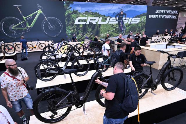 People inspect electrik bikes as they visit the booth of Crussis at the EUROBIKE 2026 fair of the international bicycle industry in Frankfurt am Main, western Germany on June 24, 2026. According to the organisers, more than 1,500 exhibitors of the bicycle and ecomobility industry from 60 countries will present their products and services during the fair running from June 24 to June 27, 2026. (Photo by Kirill KUDRYAVTSEV / AFP)