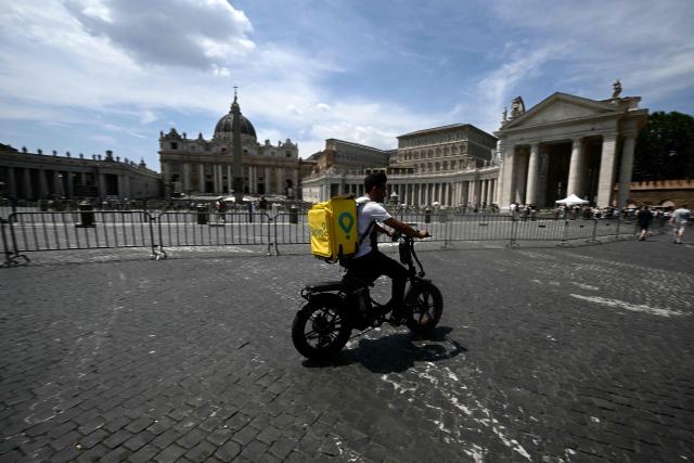 A food delivery firm Glovo's rider cycles near the Vatican during a heatwave, in Rome on June 24, 2026. The Lazio region where Rome is located has approved an order for construction workers and delivery riders not to work between 12:30 pm and 4:00 pm due to the high temperatures. But the order is widely flouted and food delivery apps do not notify their customers of any restrictions around those hours.  (Photo by Filippo MONTEFORTE / AFP)