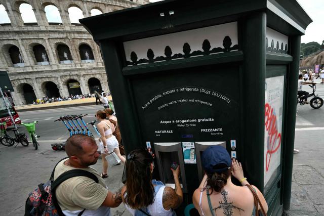 Tourists queue to fill their bottles at a public fountain displaying still and sparkling refrigerated water for free, near the Colosseum on June 24, 2026 (Photo by Andreas SOLARO / AFP)