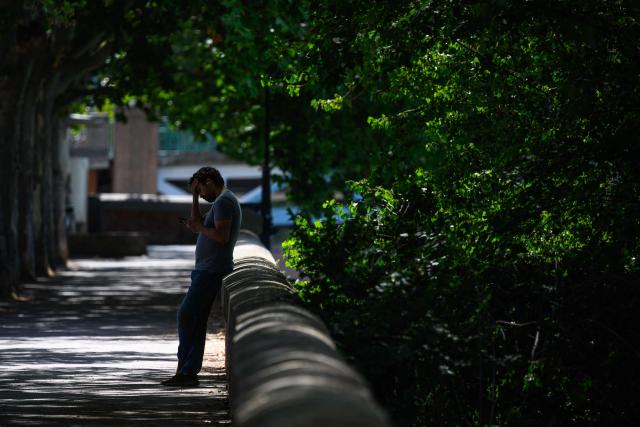 A man stands in the shade of trees on the River Garonne banks in Toulouse, south-western France on June 24, 2026, as a heatwave hits France. (Photo by Lionel BONAVENTURE / AFP)