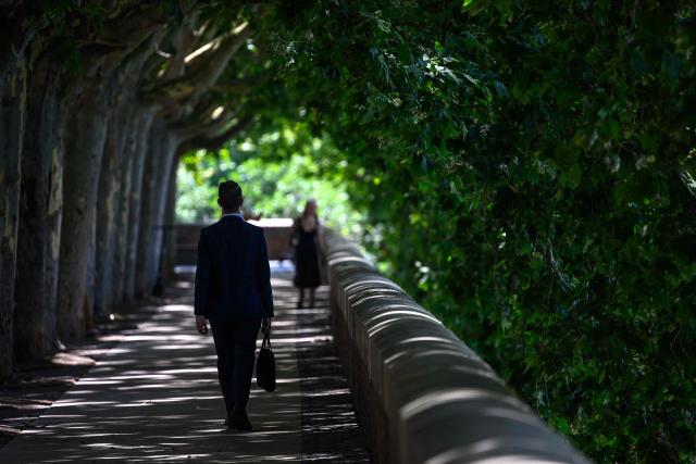 A man walks under a shade on the banks of the Garonne river in Toulouse on June 24, 2026, as a heatwave hits France. (Photo by Lionel BONAVENTURE / AFP)