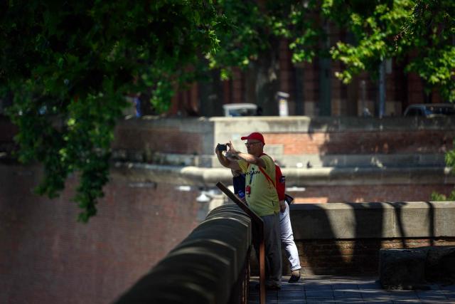 A man takes a picture under a shade on the banks of the Garonne river in Toulouse on June 24, 2026, as a heatwave hits France. (Photo by Lionel BONAVENTURE / AFP)
