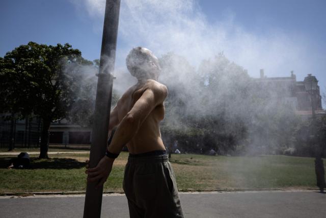 A man cools off at a mist fountain in Paris on June 24, 2026, as a heatwave hits France. (Photo by SIMON WOLFHART/STR / AFP)