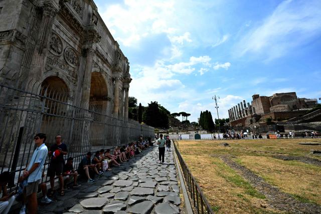 TOPSHOT - Tourists sit in the shade of the Arch of Constantine near the Colosseum in Rome on June 24, 2026. (Photo by Andreas SOLARO / AFP)