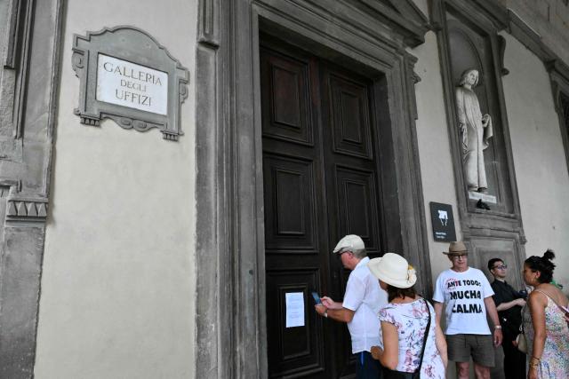 Tourists stand in front of closed doors as the Uffizi Galleries leave a note reading "Due to high temperatures the museum ha reached his maximum capacity and the ticket office will remain closed for the rest of the day", in Florence during a heatwave on June 24, 2026. (Photo by Alberto PIZZOLI / AFP)