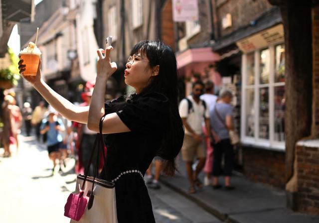 A person takes a photo of their iced drink outside a shop on the Shambles, a popular tourist destination, during a heatwave, in York, on June 24, 2026. The UK's meteorological office has issued an extremely rare red heat warning -- only issued once before -- for June24 and 25, as temperatures could soar to 40C, unprecedented for the time of the year. (Photo by Oli SCARFF / AFP)