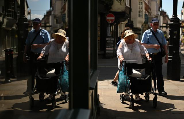 People walk past shops during a heatwave, in York, on June 24, 2026. The UK's meteorological office has issued an extremely rare red heat warning -- only issued once before -- for June24 and 25, as temperatures could soar to 40C, unprecedented for the time of the year. (Photo by Oli SCARFF / AFP)