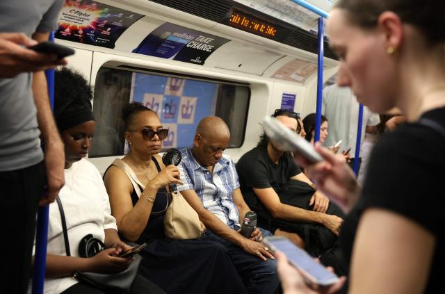 A person uses a portable fan on an underground train in central London on June 24, 2026. The UK's meteorological office has issued an extremely rare red heat warning -- only issued once before -- for June24 and 25, as temperatures could soar to 40C, unprecedented for the time of the year. (Photo by Toby Shepheard / AFP)