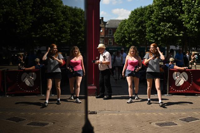 People are reflected in the window of a shop, as they walk during a heatwave, in York, on June 24, 2026. The UK's meteorological office has issued an extremely rare red heat warning -- only issued once before -- for June24 and 25, as temperatures could soar to 40C, unprecedented for the time of the year. (Photo by Oli SCARFF / AFP)