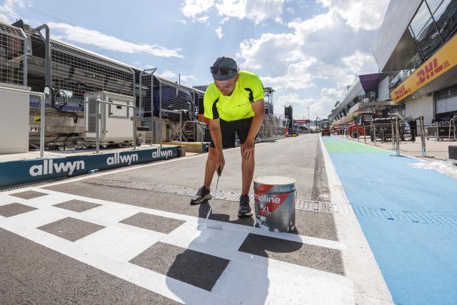 A worker paints the line for the entrance to the pits during preparations and contruction work at the Red Bull Ring race track in Spielberg, Austria on June 24, 2026, ahead of the Formula One Austrian Grand Prix. (Photo by ERWIN SCHERIAU / APA / AFP) / Austria OUT