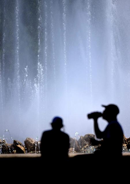People silhouette against the spray mist of a fountain on June 24, 2026 in Vienna, Austria, where temperatures reached more than 30 degrees Celsius. (Photo by HARALD SCHNEIDER / APA / AFP) / Austria OUT