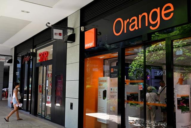 A customer walks near the entrance of a SFR telecom agency retail shop, located next to an Orange telecom shop, in Beziers, Southern France, on June 24, 2026. Three of France's mobile operators (Bouygues Telecom, Free and Orange) have agreed a joint bid worth 20.4 billion euros ($23.5 billion) for rival SFR, owned by indebted French-Luxembourg telco group Altice. (Photo by Gabriel BOUYS / AFP)