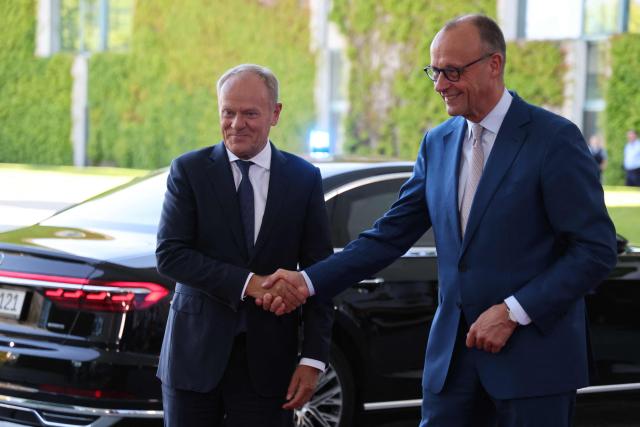 German Chancellor Friedrich Merz (R) welcomes Polish Prime Minister Donald Tusk as he arrives for a meeting with state leaders of the European Group of Five (E5) and the NATO Secretary General on June 24, 2026 at the Chancellery in Berlin, Germany. (Photo by Ludovic MARIN / AFP)