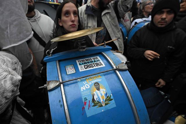 A sticker depicting late Argentine football legend Diego Maradona is seen on the bass drum of a supporter of former Argentine president (2007–2015) Cristina Kirchner as she waves from the balcony of her home while on house arrest in Buenos Aires on June 10, 2026, the day before the beginning of the FIFA World Cup 2026. (Photo by Luis ROBAYO / AFP)