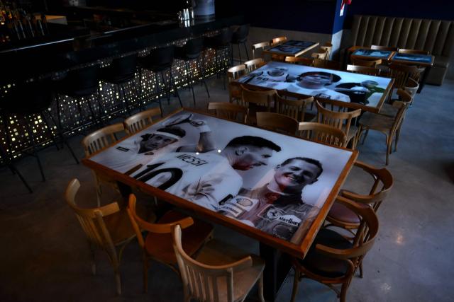 Tables dipicting Argentine football star Lionel Messi (bottom) and late Argentine football legend Diego Maradona are seen at a bar in Buenos Aires on June 23, 2026, during the FIFA World Cup 2026. (Photo by Luis ROBAYO / AFP)