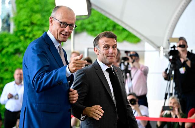 German Chancellor Friedrich Merz (L) welcomes France's President Emmanuel Macron as he arrives for a meeting with state leaders of the European Group of Five (E5) and the NATO Secretary General on June 24, 2026 at the Chancellery in Berlin, Germany. (Photo by Tobias SCHWARZ / AFP)