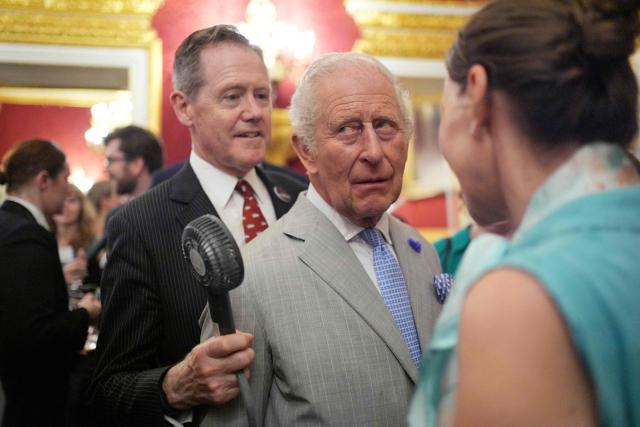 Vice Admiral Sir Tony Johnstone-Burt, Master of the Household to the Sovereign holds a small battery powered fan for Britain's King Charles III as he attends a London Climate Week reception, hosted by the Department for Energy Security and Net Zero (DESNZ), at St James's Palace, London on June 24, 2026. (Photo by Yui Mok / POOL / AFP)