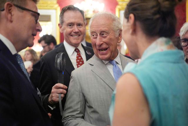 Vice Admiral Sir Tony Johnstone-Burt, Master of the Household to the Sovereign holds a small battery powered fan for Britain's King Charles III as he attends a London Climate Week reception, hosted by the Department for Energy Security and Net Zero (DESNZ), at St James's Palace, London on June 24, 2026. (Photo by Yui Mok / POOL / AFP)