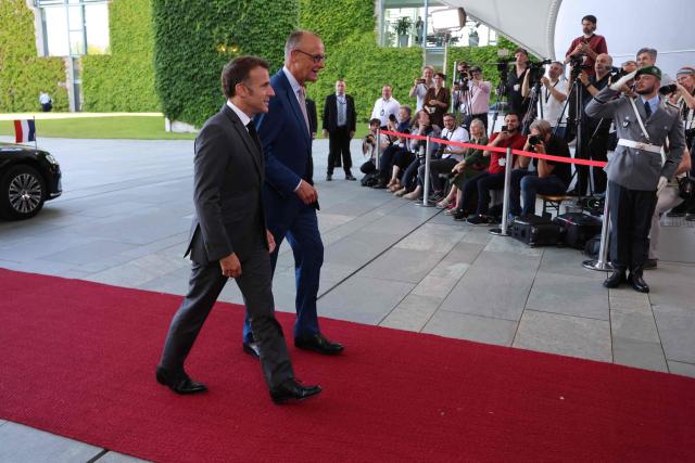 German Chancellor Friedrich Merz (L) welcomes France's President Emmanuel Macron as he arrives for a meeting with state leaders of the European Group of Five (E5) and the NATO Secretary General on June 24, 2026 at the Chancellery in Berlin, Germany. (Photo by Ludovic MARIN / AFP)