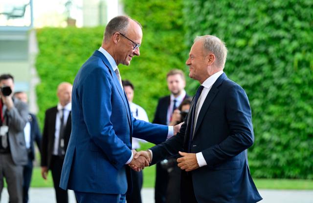 German Chancellor Friedrich Merz (L) welcomes Polish Prime Minister Donald Tusk as he arrives for a meeting with state leaders of the European Group of Five (E5) and the NATO Secretary General on June 24, 2026 at the Chancellery in Berlin, Germany. (Photo by John MACDOUGALL / AFP)