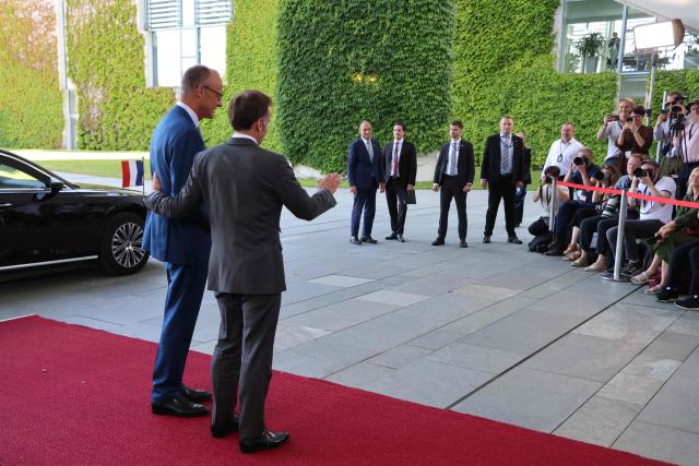 German Chancellor Friedrich Merz (L) welcomes France's President Emmanuel Macron as he arrives for a meeting with state leaders of the European Group of Five (E5) and the NATO Secretary General on June 24, 2026 at the Chancellery in Berlin, Germany. (Photo by Ludovic MARIN / AFP)