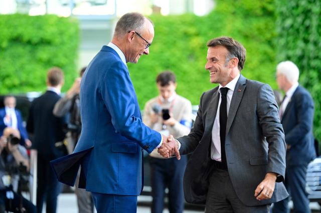 German Chancellor Friedrich Merz (L) welcomes France's President Emmanuel Macron as he arrives for a meeting with state leaders of the European Group of Five (E5) and the NATO Secretary General on June 24, 2026 at the Chancellery in Berlin, Germany. (Photo by John MACDOUGALL / AFP)