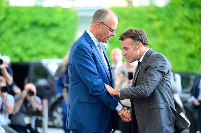 German Chancellor Friedrich Merz (L) welcomes France's President Emmanuel Macron as he arrives for a meeting with state leaders of the European Group of Five (E5) and the NATO Secretary General on June 24, 2026 at the Chancellery in Berlin, Germany. (Photo by John MACDOUGALL / AFP)
