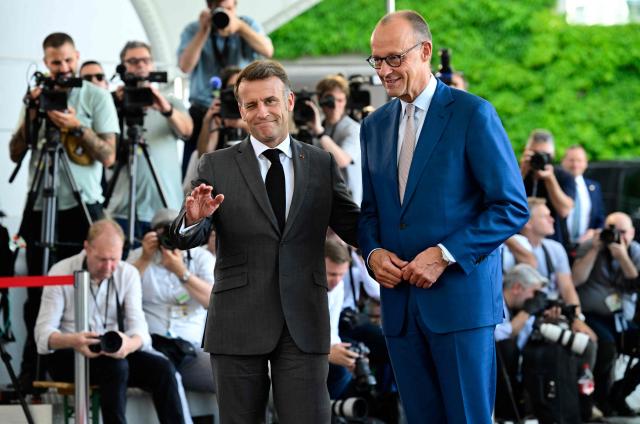 German Chancellor Friedrich Merz (R) welcomes France's President Emmanuel Macron as he arrives for a meeting with state leaders of the European Group of Five (E5) and the NATO Secretary General on June 24, 2026 at the Chancellery in Berlin, Germany. (Photo by John MACDOUGALL / AFP)