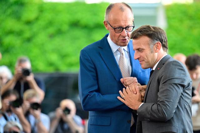 German Chancellor Friedrich Merz (L) welcomes France's President Emmanuel Macron as he arrives for a meeting with state leaders of the European Group of Five (E5) and the NATO Secretary General on June 24, 2026 at the Chancellery in Berlin, Germany. (Photo by John MACDOUGALL / AFP)