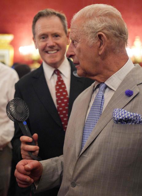 Vice Admiral Sir Tony Johnstone-Burt, Master of the Household to the Sovereign holds a small battery powered fan for Britain's King Charles III as he attends a London Climate Week reception, hosted by the Department for Energy Security and Net Zero (DESNZ), at St James's Palace, London on June 24, 2026. (Photo by Yui Mok / POOL / AFP)