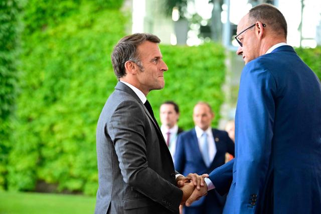German Chancellor Friedrich Merz (L) welcomes France's President Emmanuel Macron as he arrives for a meeting with state leaders of the European Group of Five (E5) and the NATO Secretary General on June 24, 2026 at the Chancellery in Berlin, Germany. (Photo by Tobias SCHWARZ / AFP)