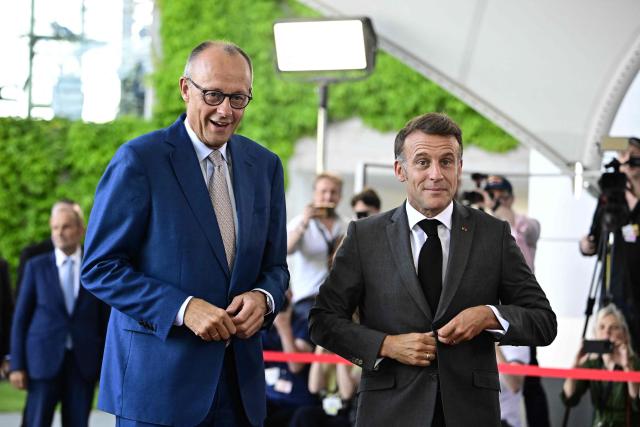 German Chancellor Friedrich Merz (L) welcomes France's President Emmanuel Macron as he arrives for a meeting with state leaders of the European Group of Five (E5) and the NATO Secretary General on June 24, 2026 at the Chancellery in Berlin, Germany. (Photo by Tobias SCHWARZ / AFP)