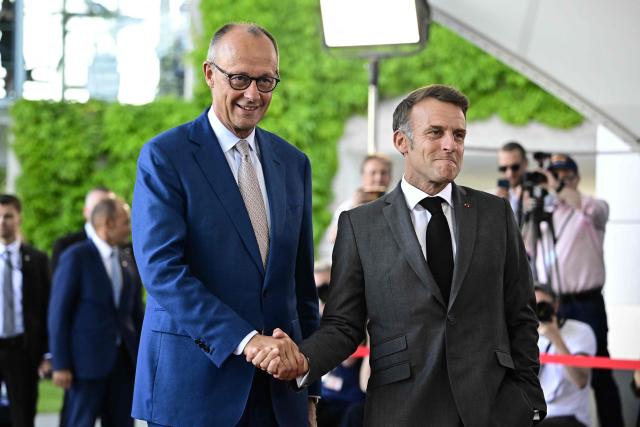 German Chancellor Friedrich Merz (L) welcomes France's President Emmanuel Macron as he arrives for a meeting with state leaders of the European Group of Five (E5) and the NATO Secretary General on June 24, 2026 at the Chancellery in Berlin, Germany. (Photo by Tobias SCHWARZ / AFP)
